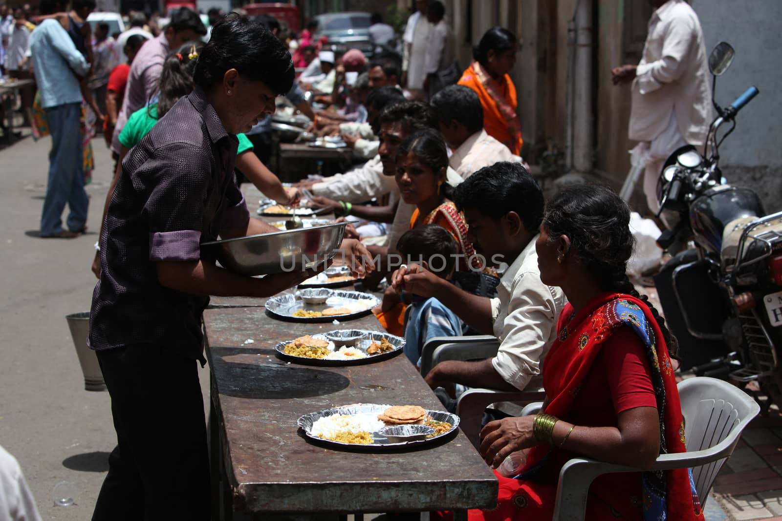 Pune, India - July 11, 2015: Indian pilgrims known as warkaris been served free meal on the side of the road during Wari festival in India.