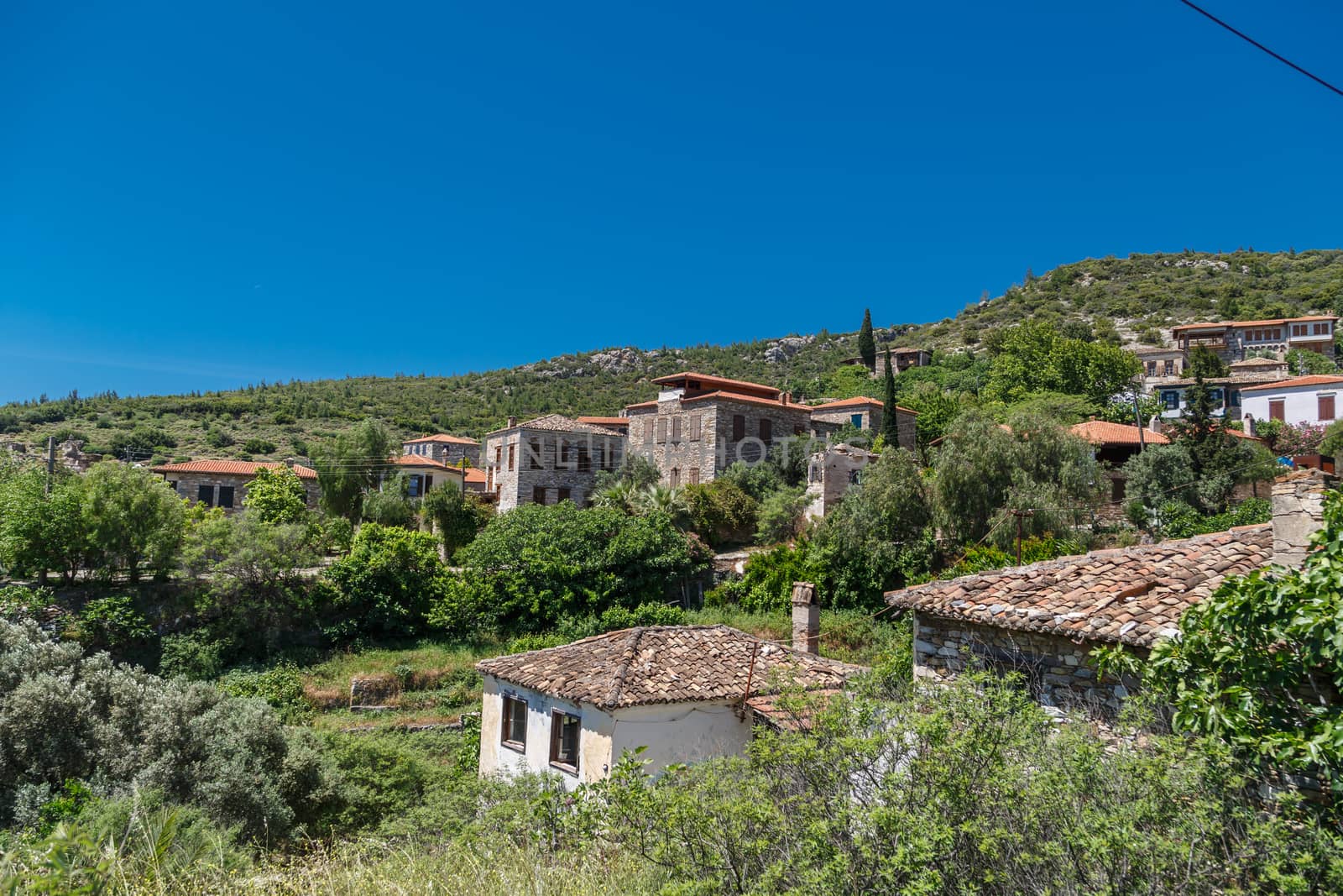 Landscape view of historical Doganbeyli village in Aydin, Turkey with historical small stone houses on bright blue sky background.