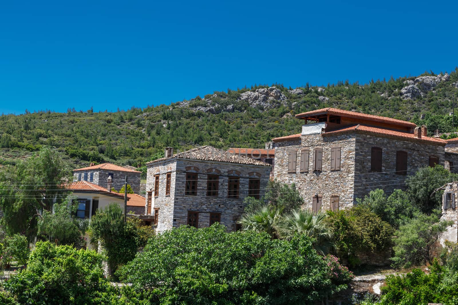 Landscape view of historical Doganbeyli village in Aydin, Turkey with historical small stone houses on bright blue sky background.