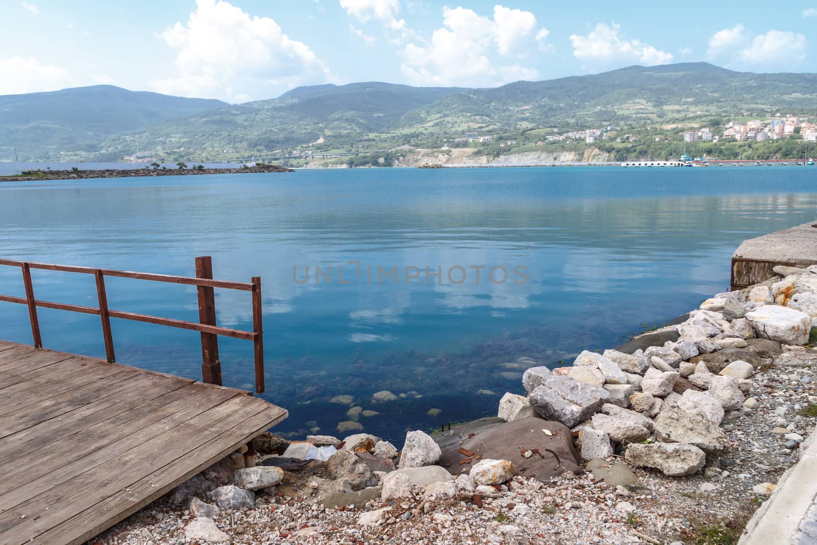 Close up view of Gerze port along Black Sea with high mountains and smal houses on cloudy blue sky background.