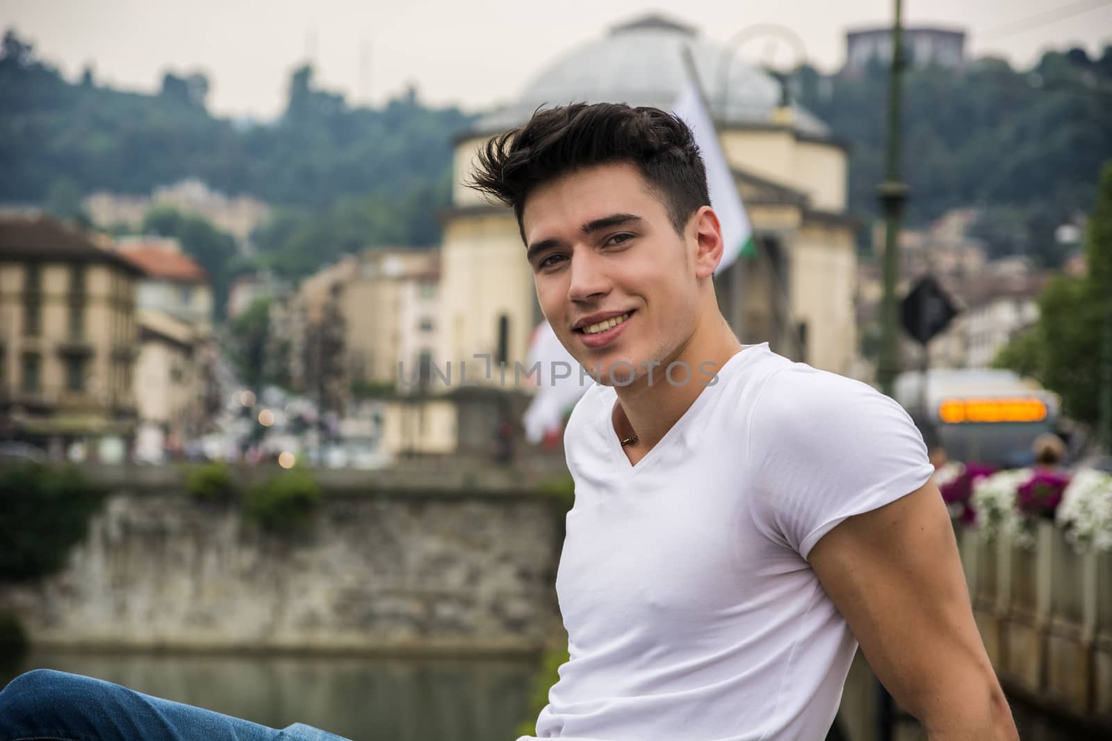 Handsome young man in city street, looking at camera with a smile