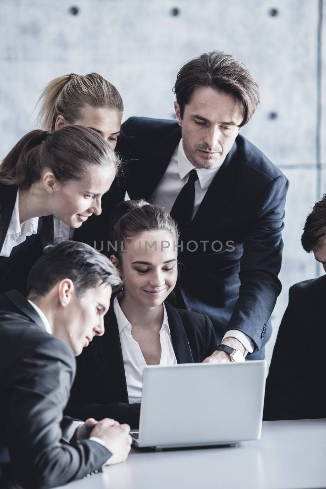 Group of business people look together at laptop in office