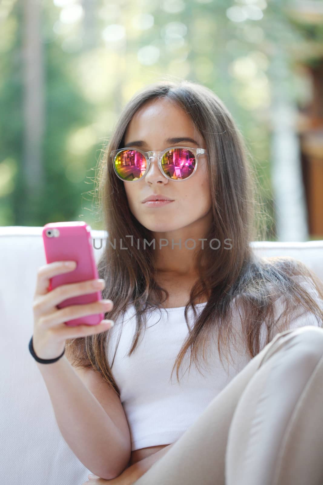 Beautiful young girl with smartphone sitting outdoors