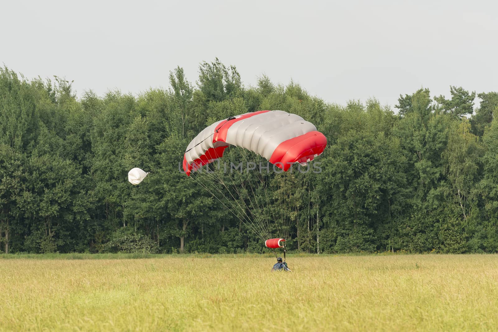 A just landed parachutist with a mattress-shaped parachute in a field
