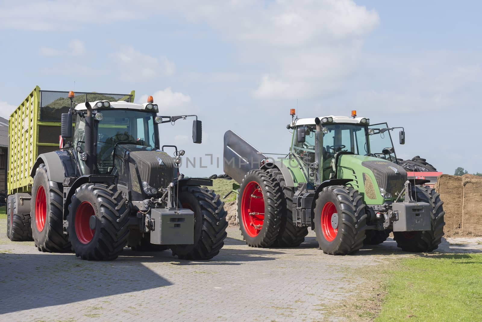 pause during silage of shredded grass with two tractors and a loader wagon