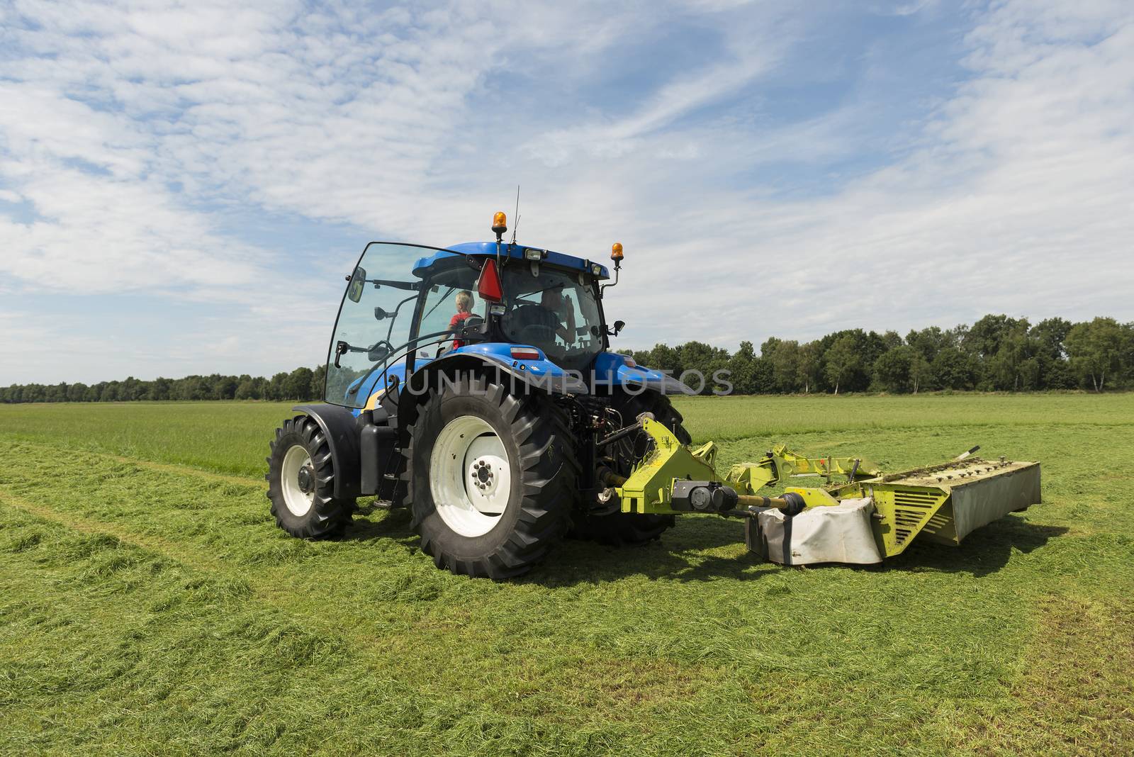 pasture mowing with blue tractor and mower