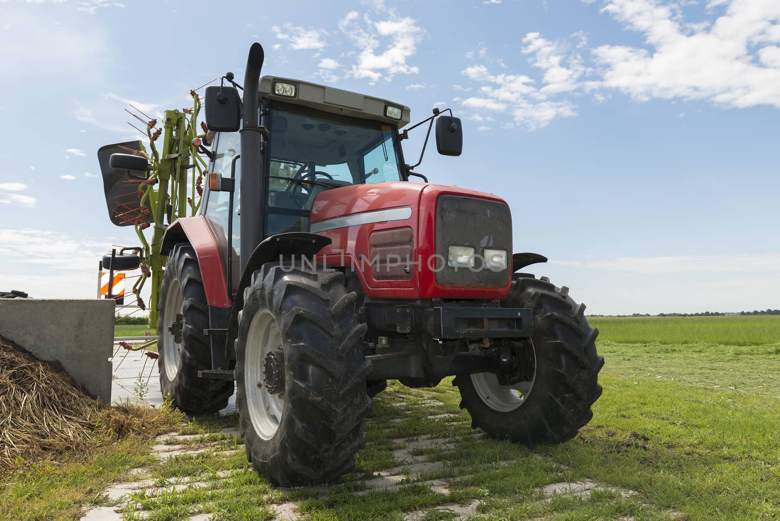 red tractor with tedder nearby a field