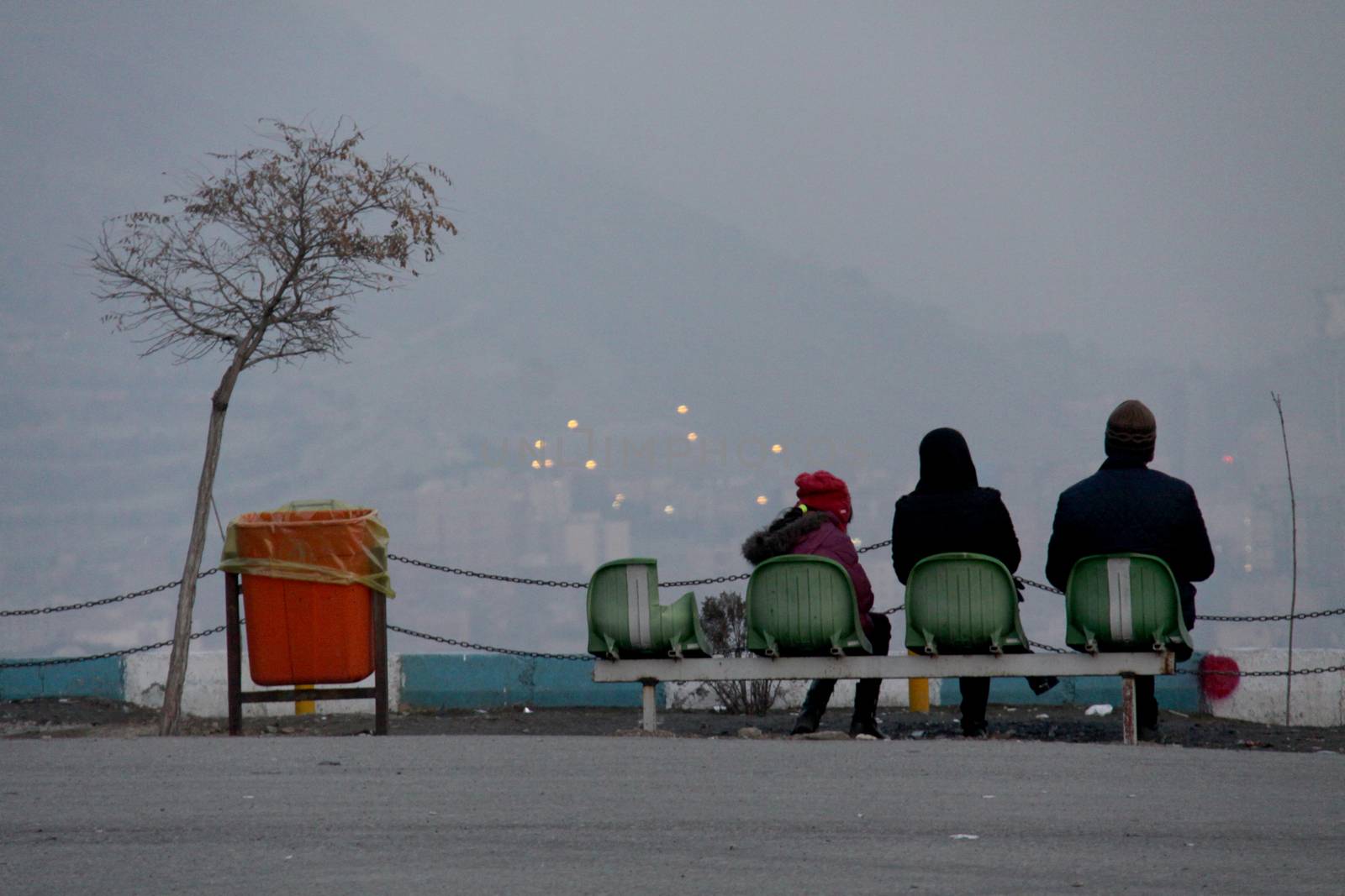 IRAN, Tehran: People sit and look over the skyline of Tehran on December 29, 2015, as thick clouds of pollution hang over the city.The city of an estimated 14 million people was also forced to close schools last week due to the lingering pollution.