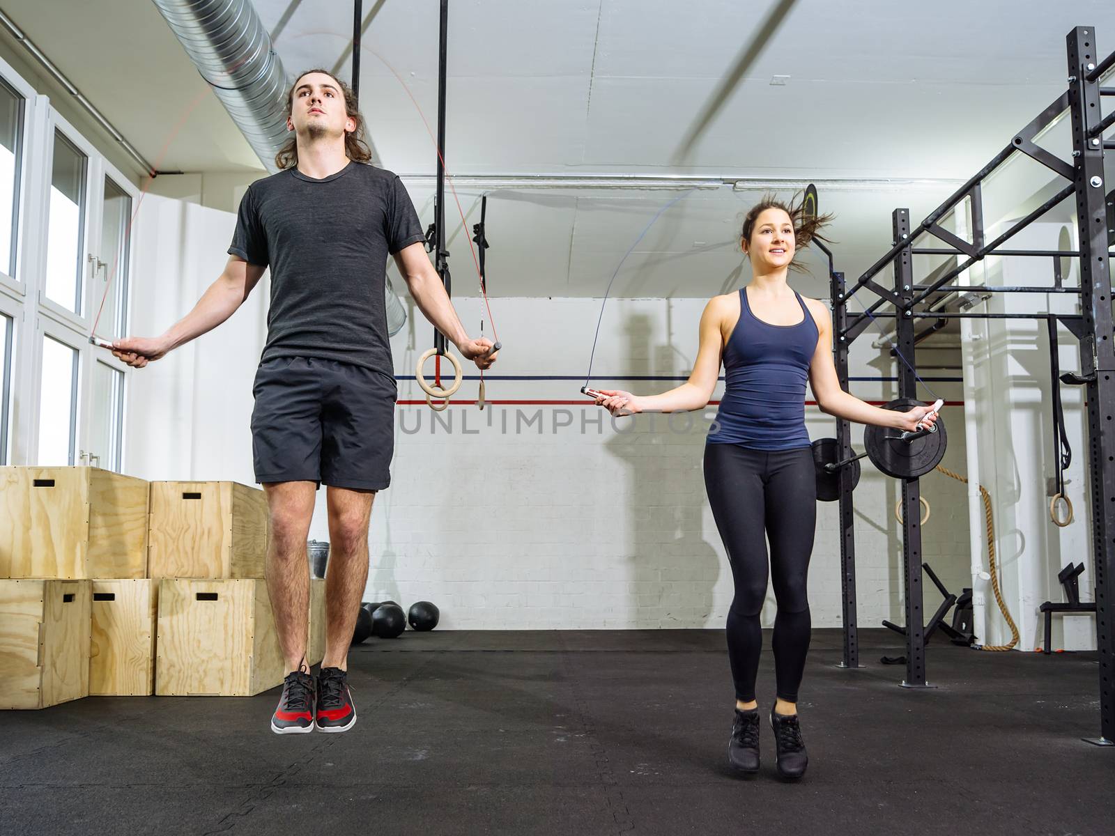 Woman and man skipping rope at the gym by sumners