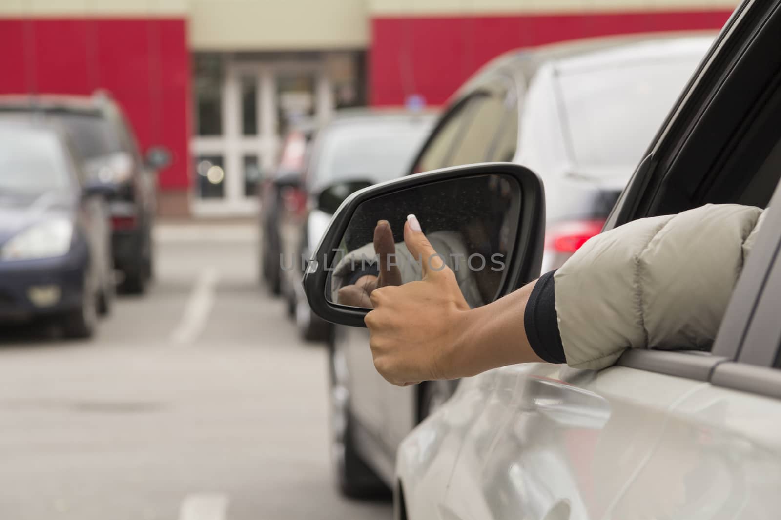 girl makes a gesture with his hand out the window of a passenger car white