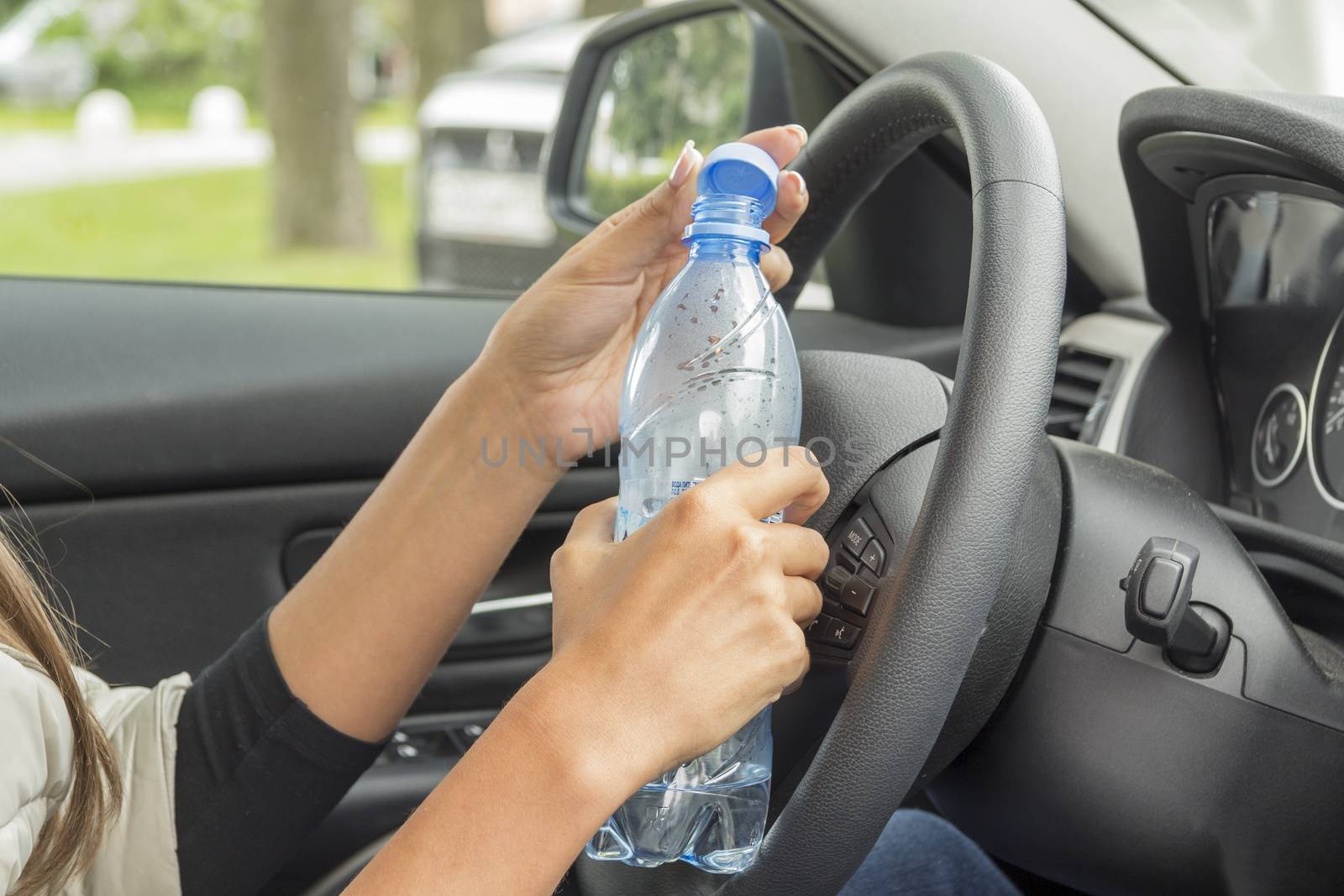 the girl in the cabin of the car holding a bottle of water