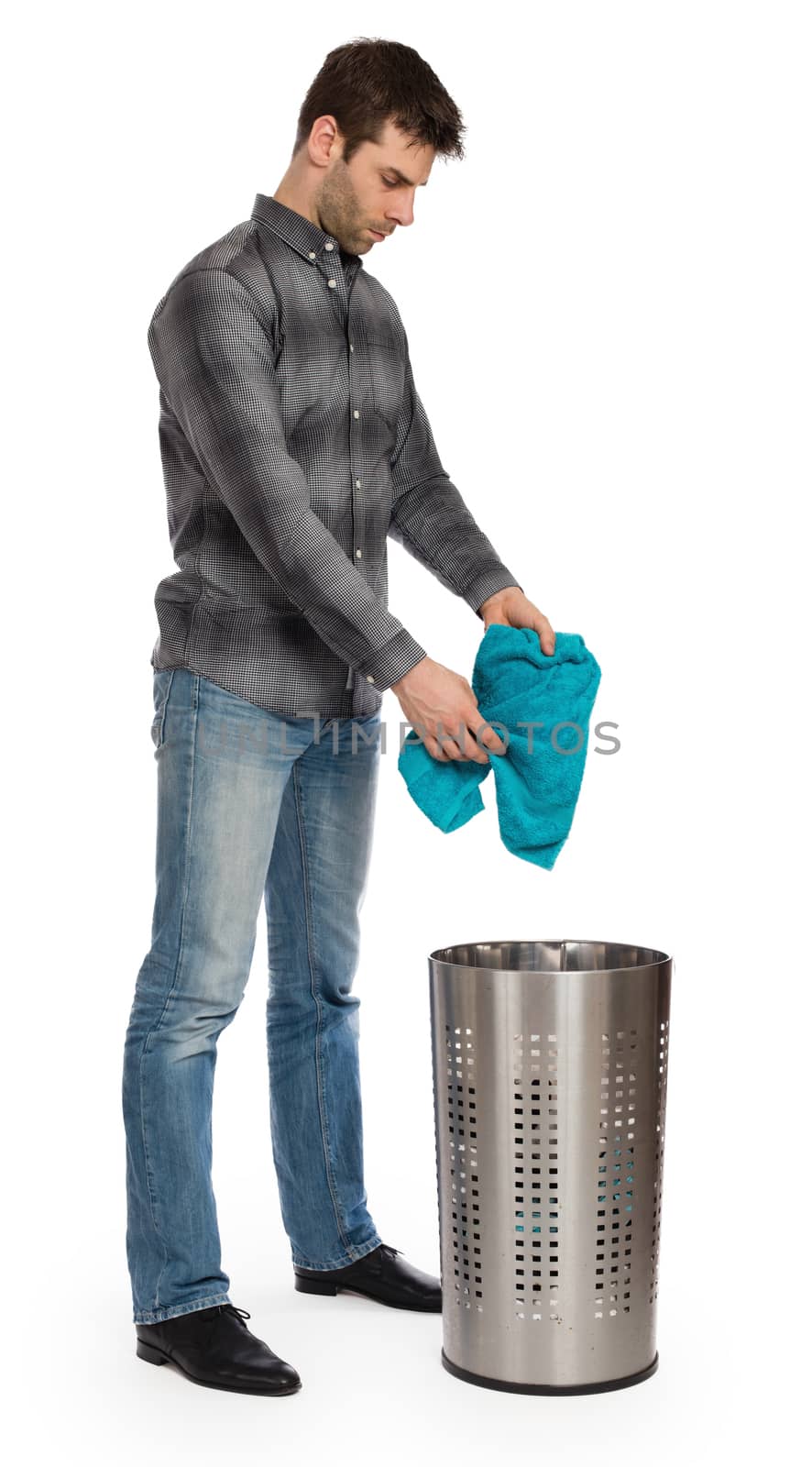 Young man putting a dirty towel in a laundry basket, isolated