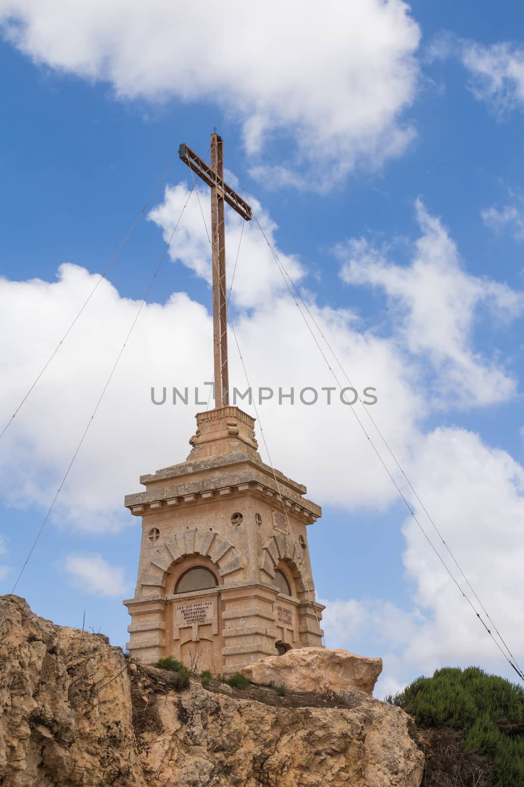 The Laferla Cross is an early 20th-century religious landmark within the outskirts of Siggiewi, at mediterranean island Malta. Blue sky with white clouds.