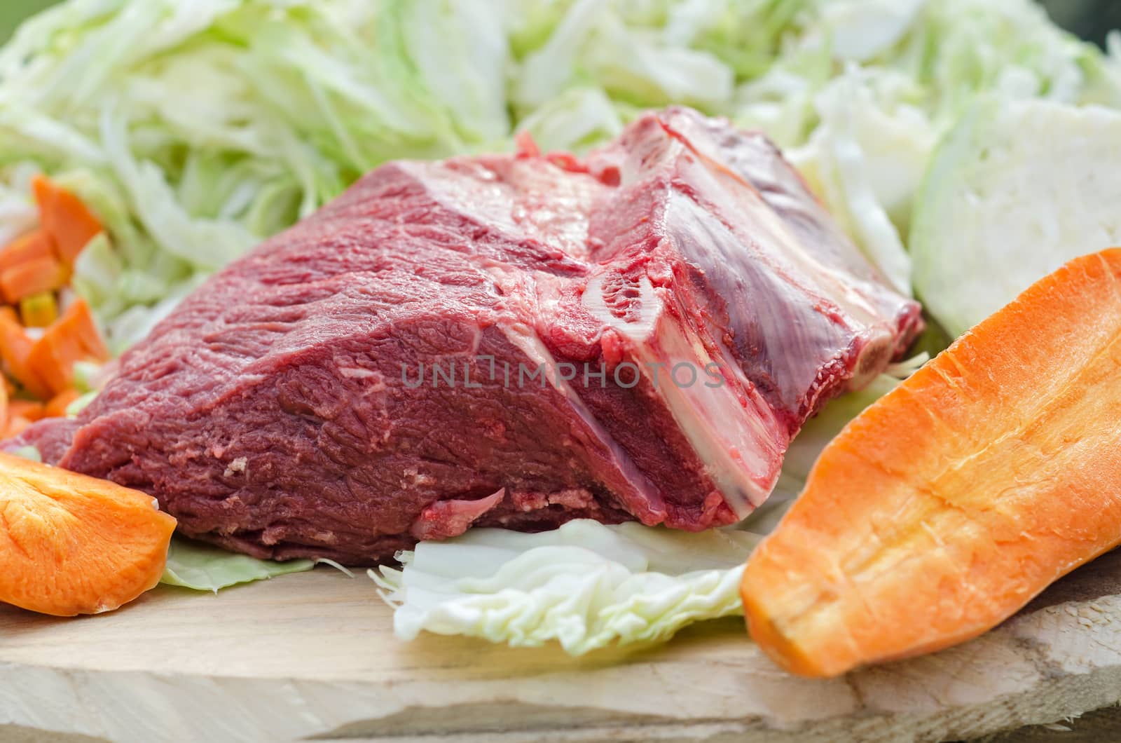 A big piece of raw beef and vegetables on a rough Board, ingredients for cooking at the picnic