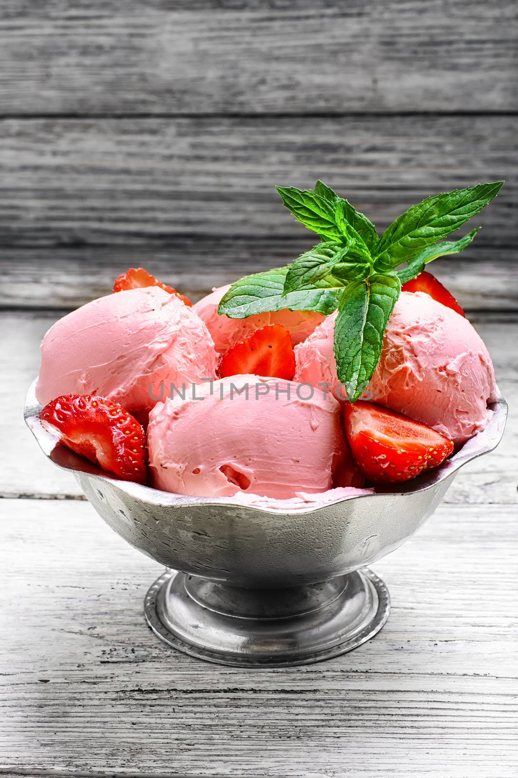 Ice cream with strawberries and leaves of mint in the iron bowl