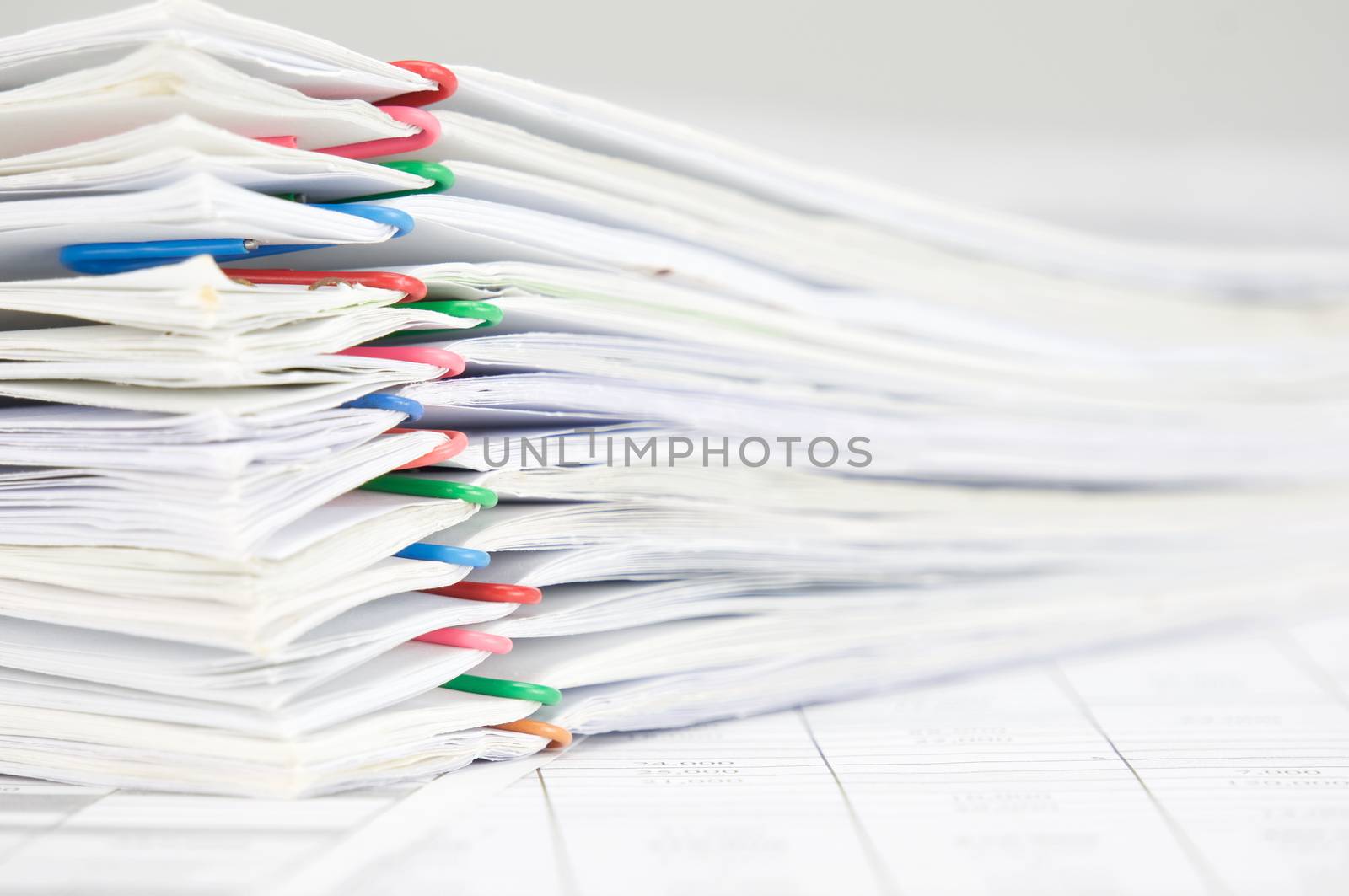 Pile overload paperwork of report with colorful paperclip on finance account with white background.