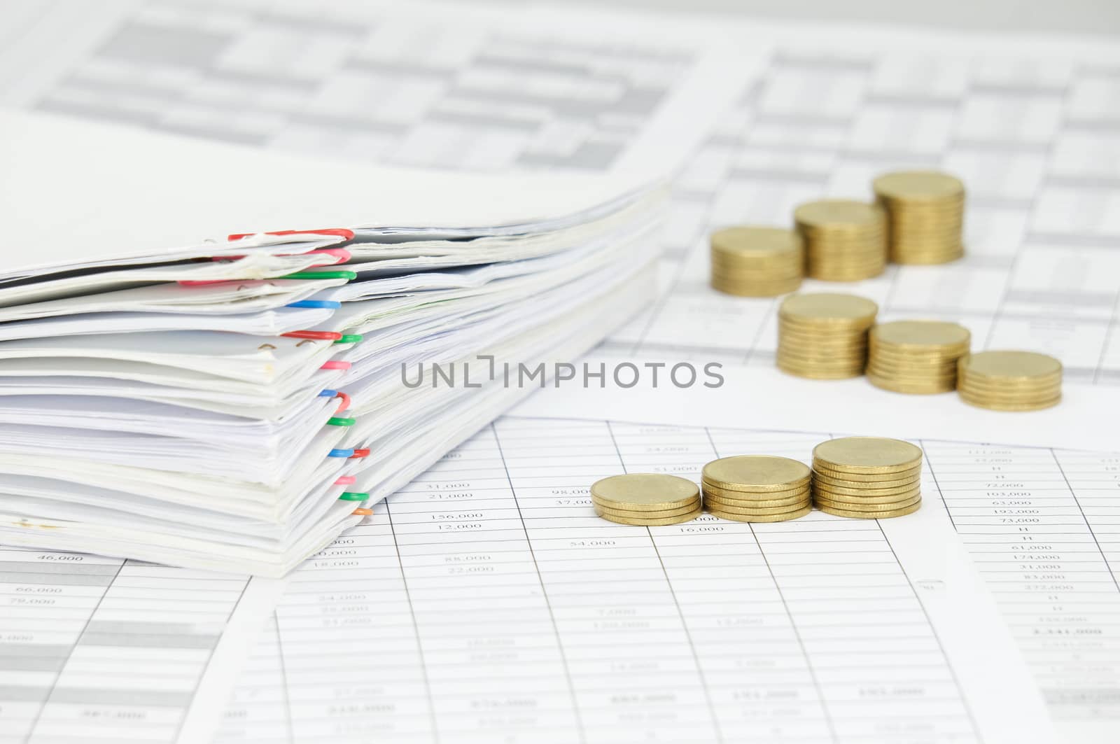 Step pile of gold coins and overload of paperwork with colorful paperclip on finance account with white background.