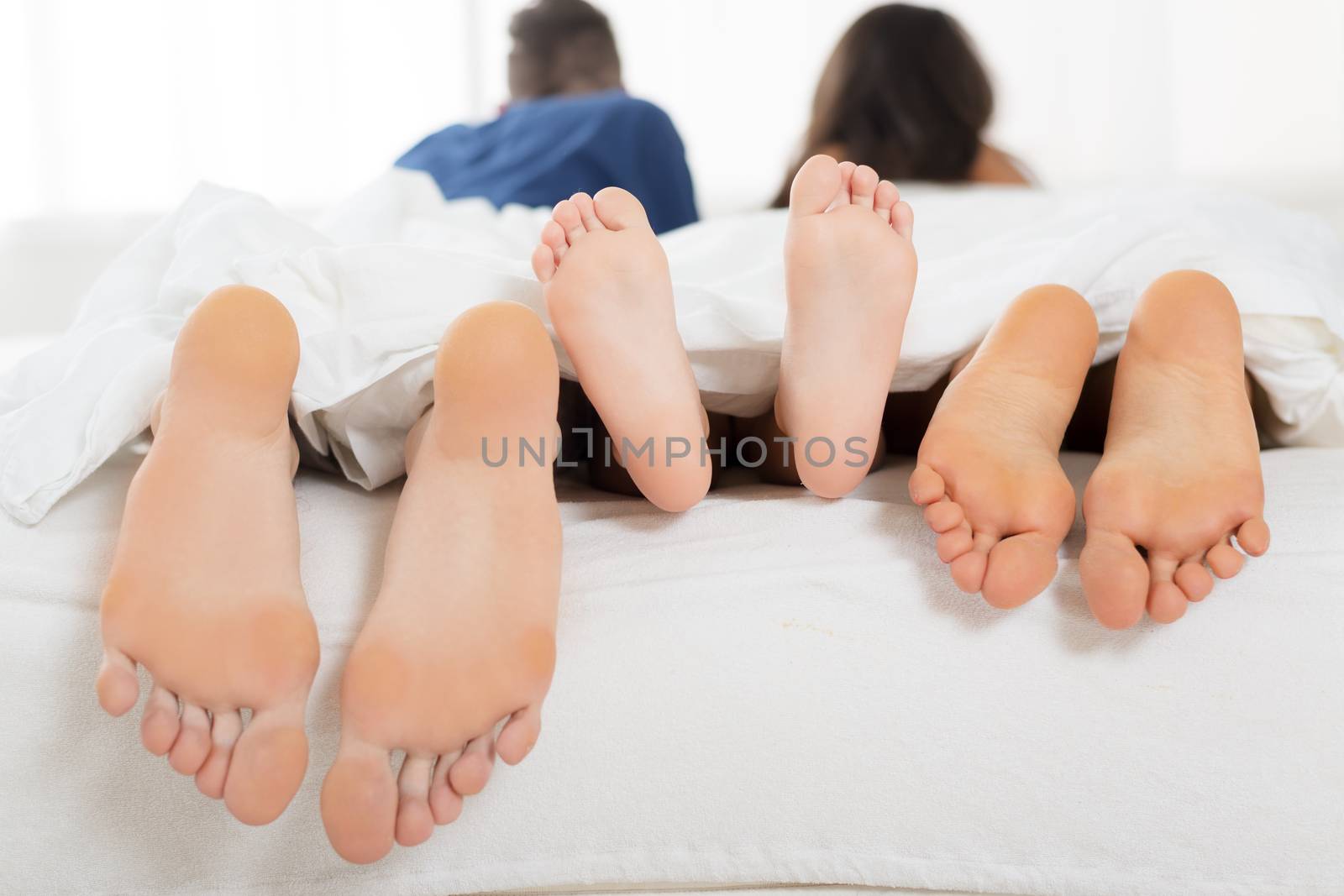 Photograph feet of the child and the parents who enjoy lying in bed.