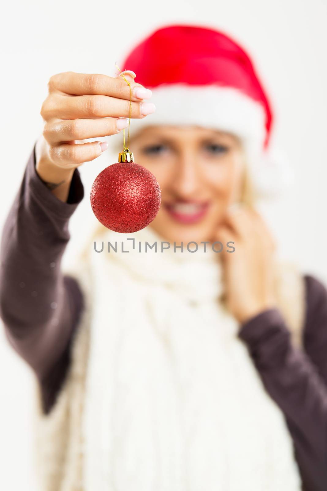 Christmas decoration in hand of a beautiful young woman whose smiling face is out of focus.