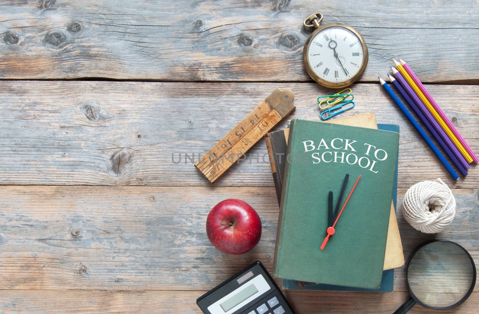 Book with clock hands with stationery accessories on a wooden and space for text 