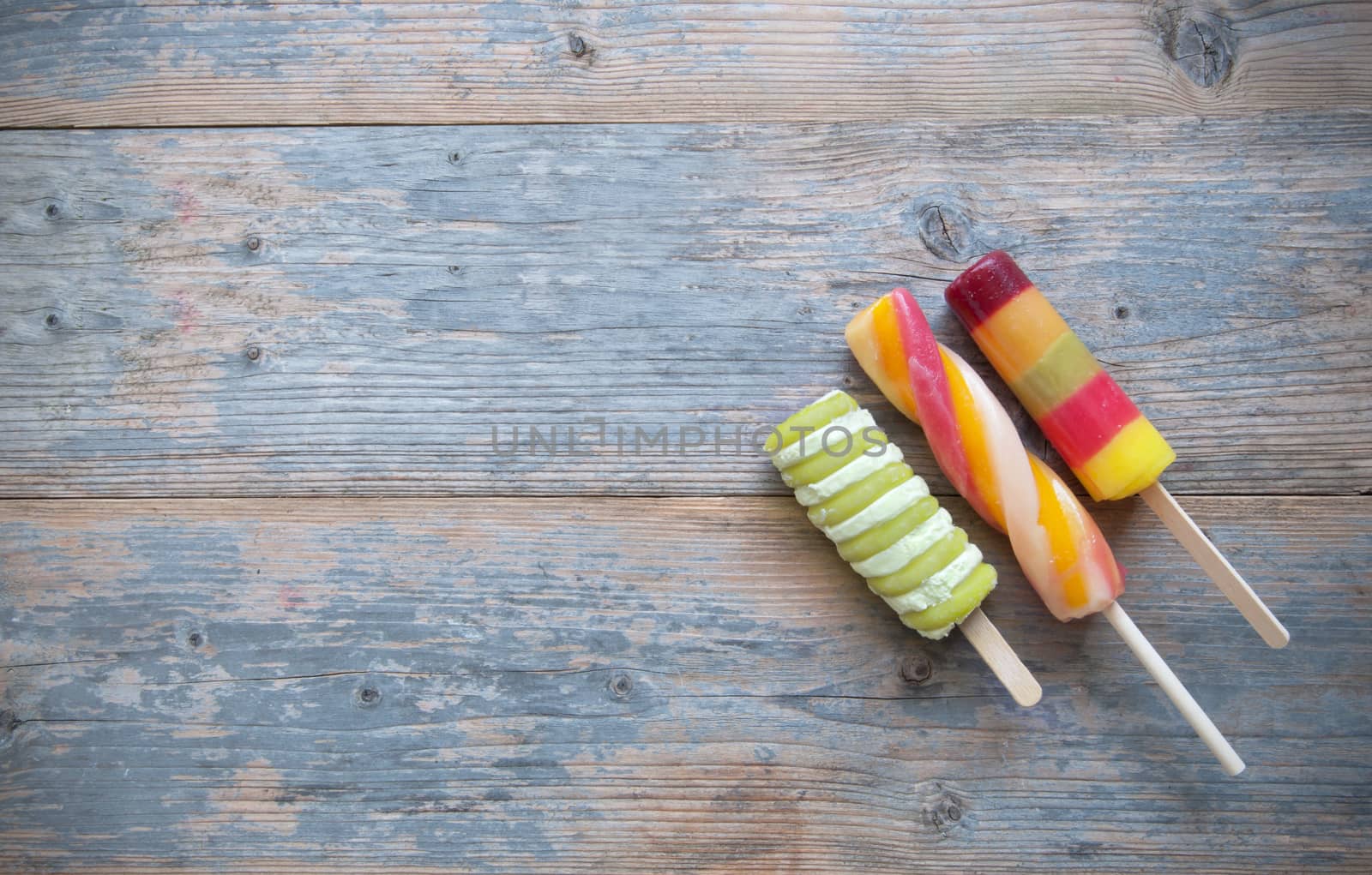 Three frozen ice lollies on a wooden background