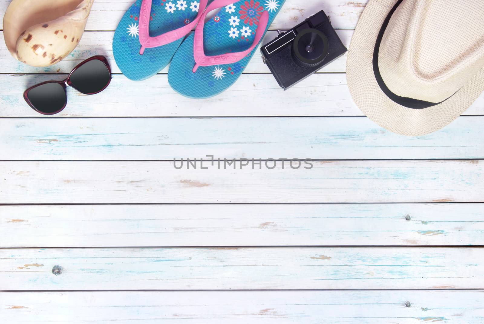 Vacation items, inluding sunglasses, and camera, over a wooden background with space