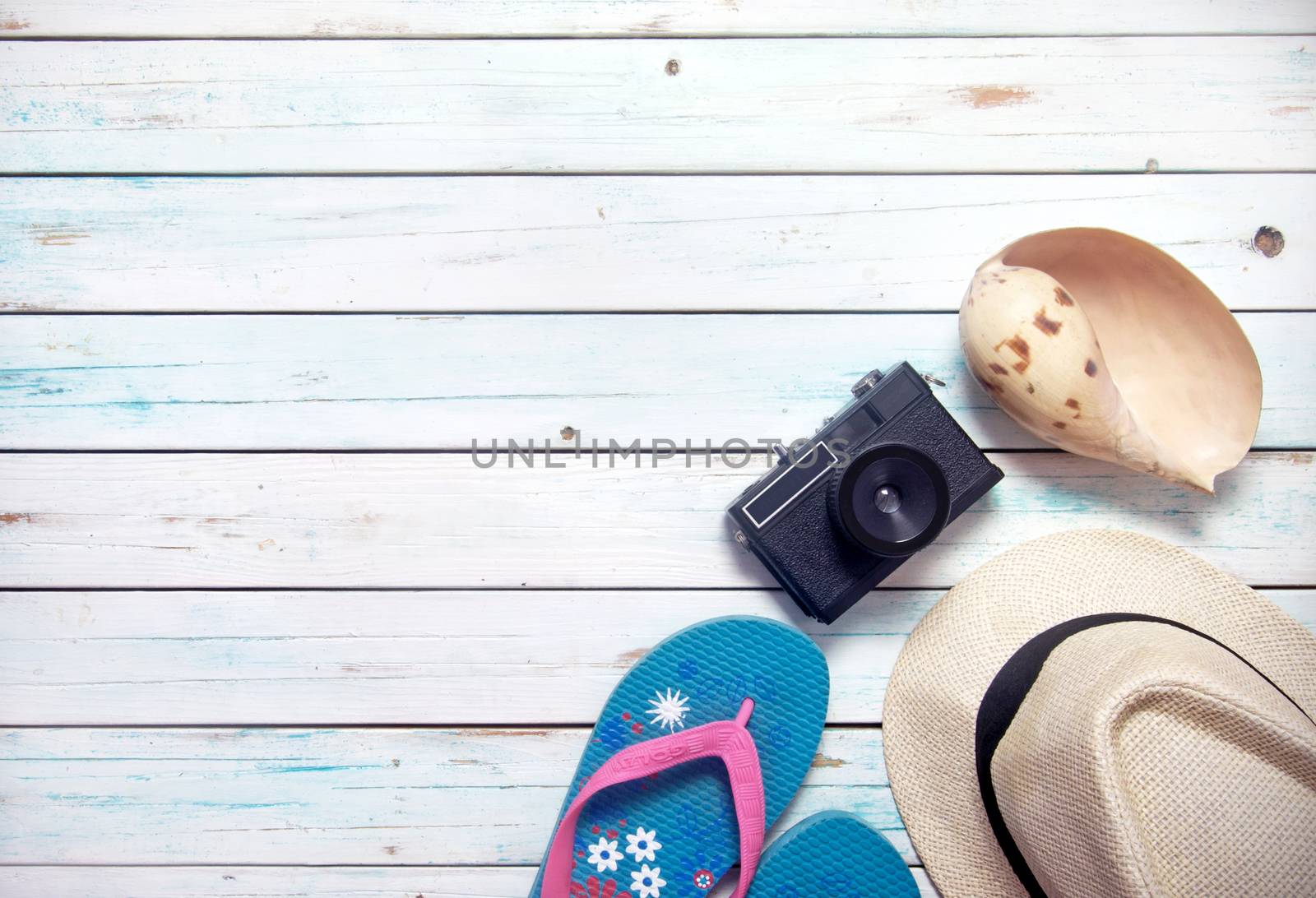 Vacation items, inluding sunglasses, and camera, on white wooden planks with space