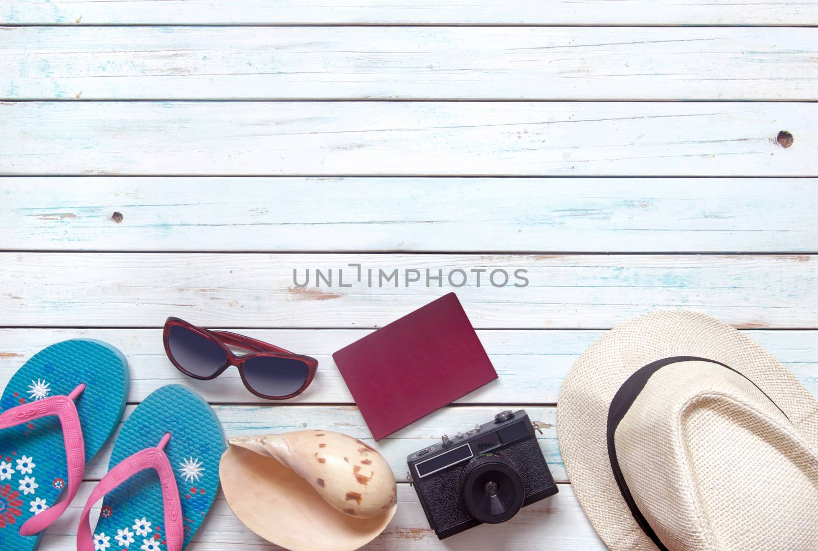 Vacation items, inluding sunglasses, passport and camera, over a wooden background with space  