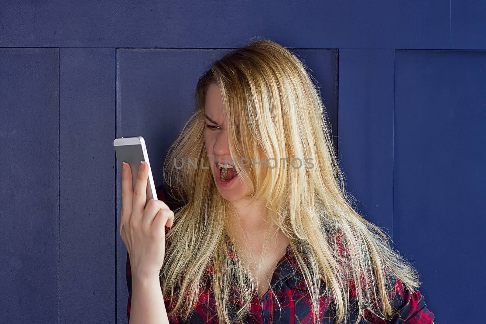 Portrait angry young woman screaming on mobile phone by victosha