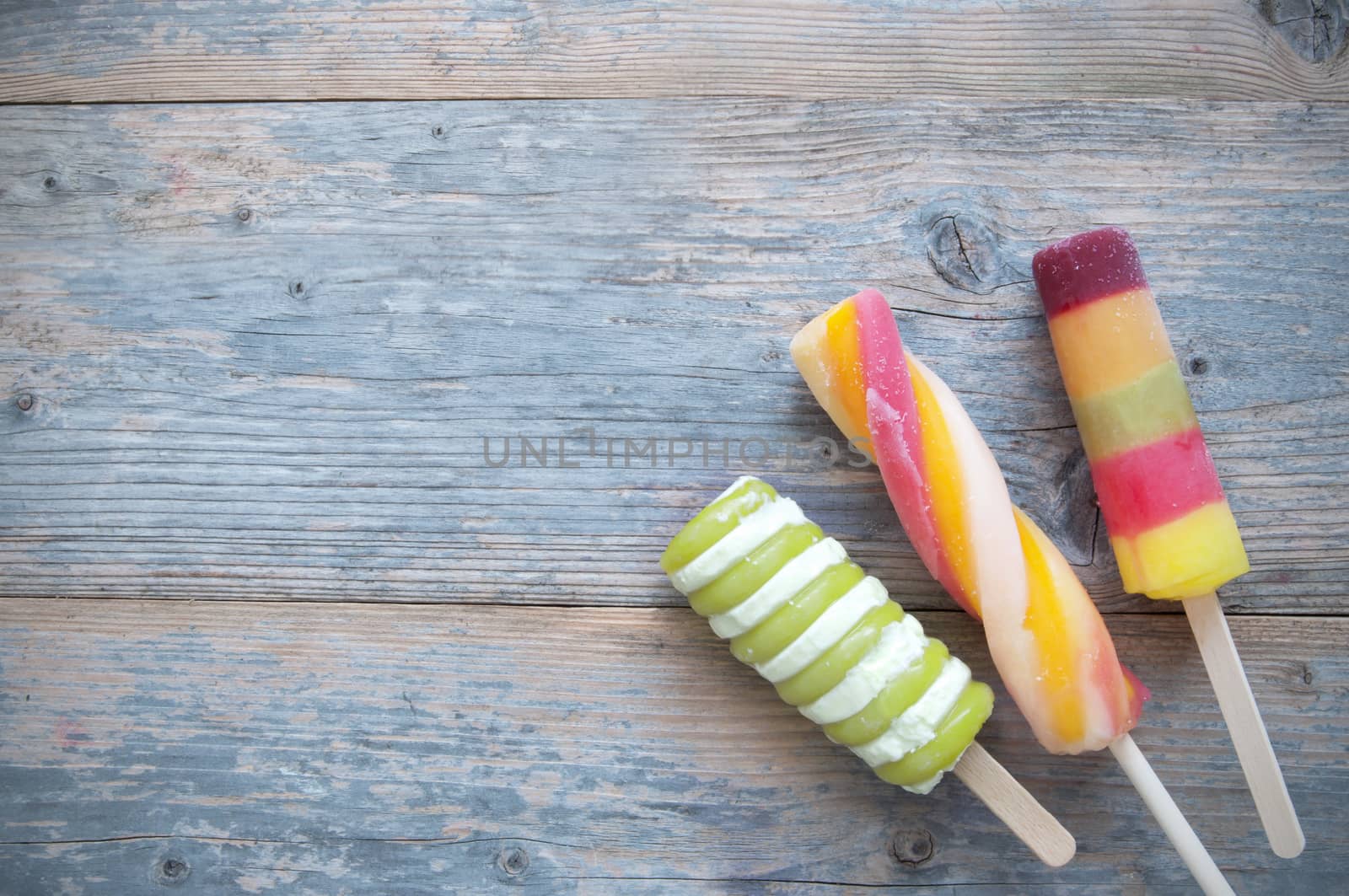 Three frozen ice lolly flavors on a wooden background