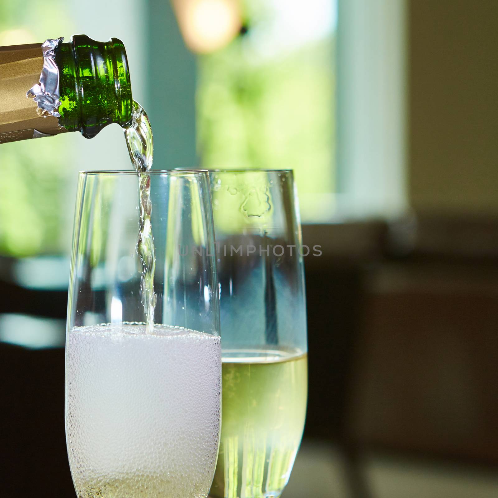 Champagne pouring in two elegant glasses. Closeup
