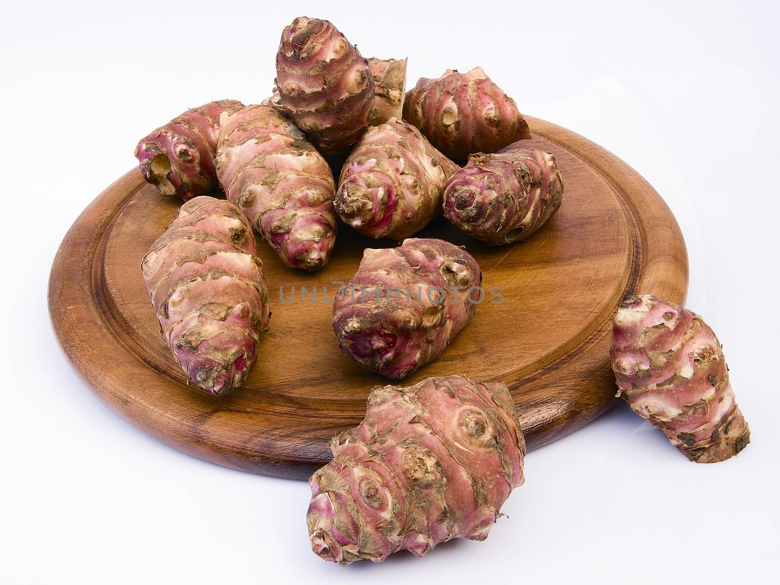 Topinambur root  on a round board. Also known as Jerusalem artichoke (Helianthus tuberosus). Edible rhizome native to North America with a taste similar to the artichoke.