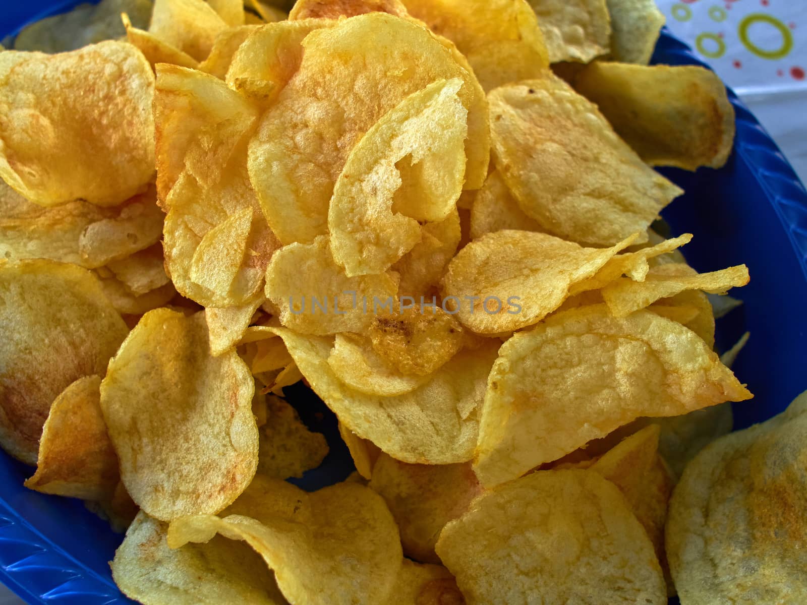 Potato chips crisps in served on a blue plate taken in closeup