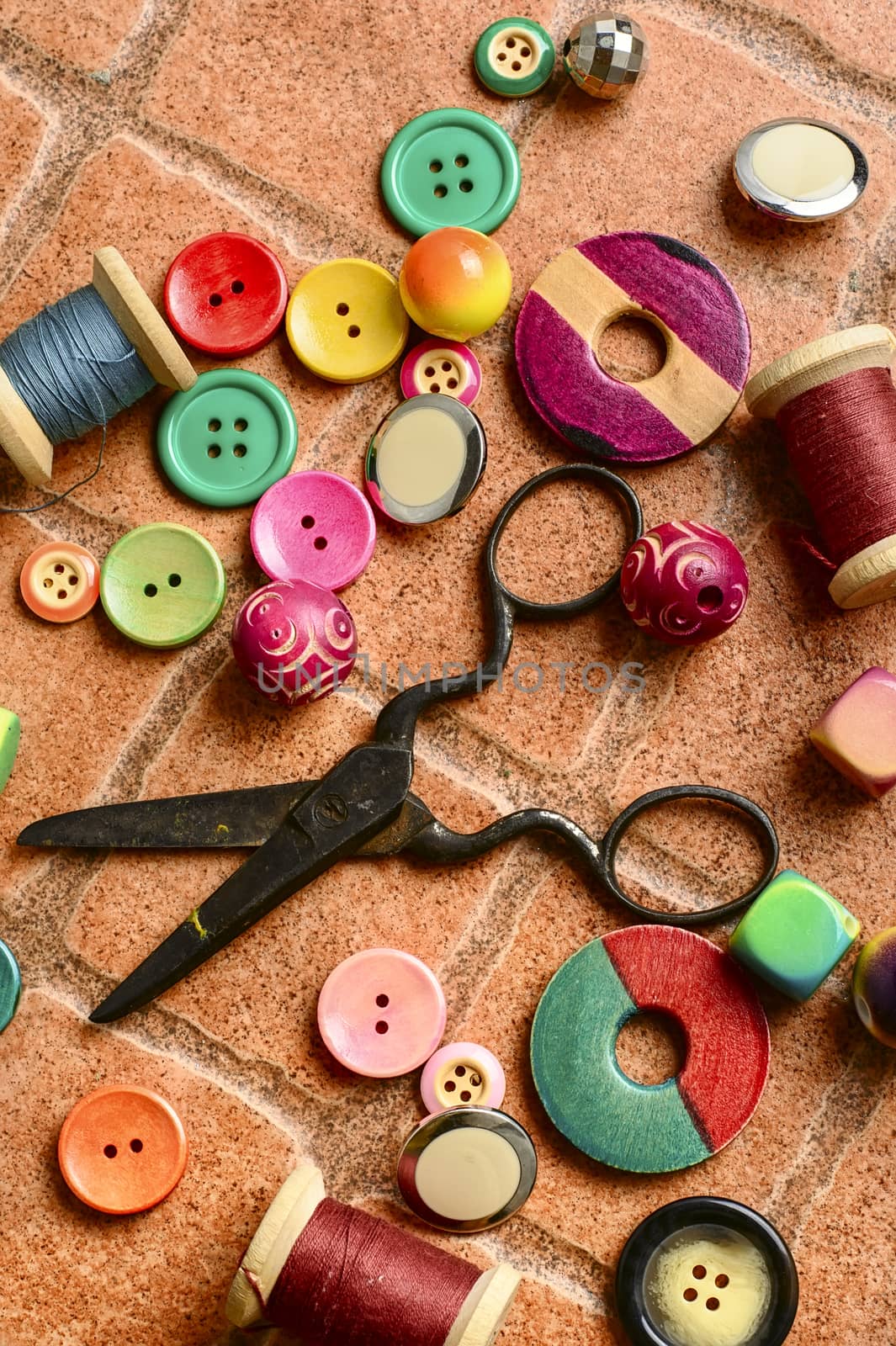 Sewing kit from buttons,beads and scissors on the brick background