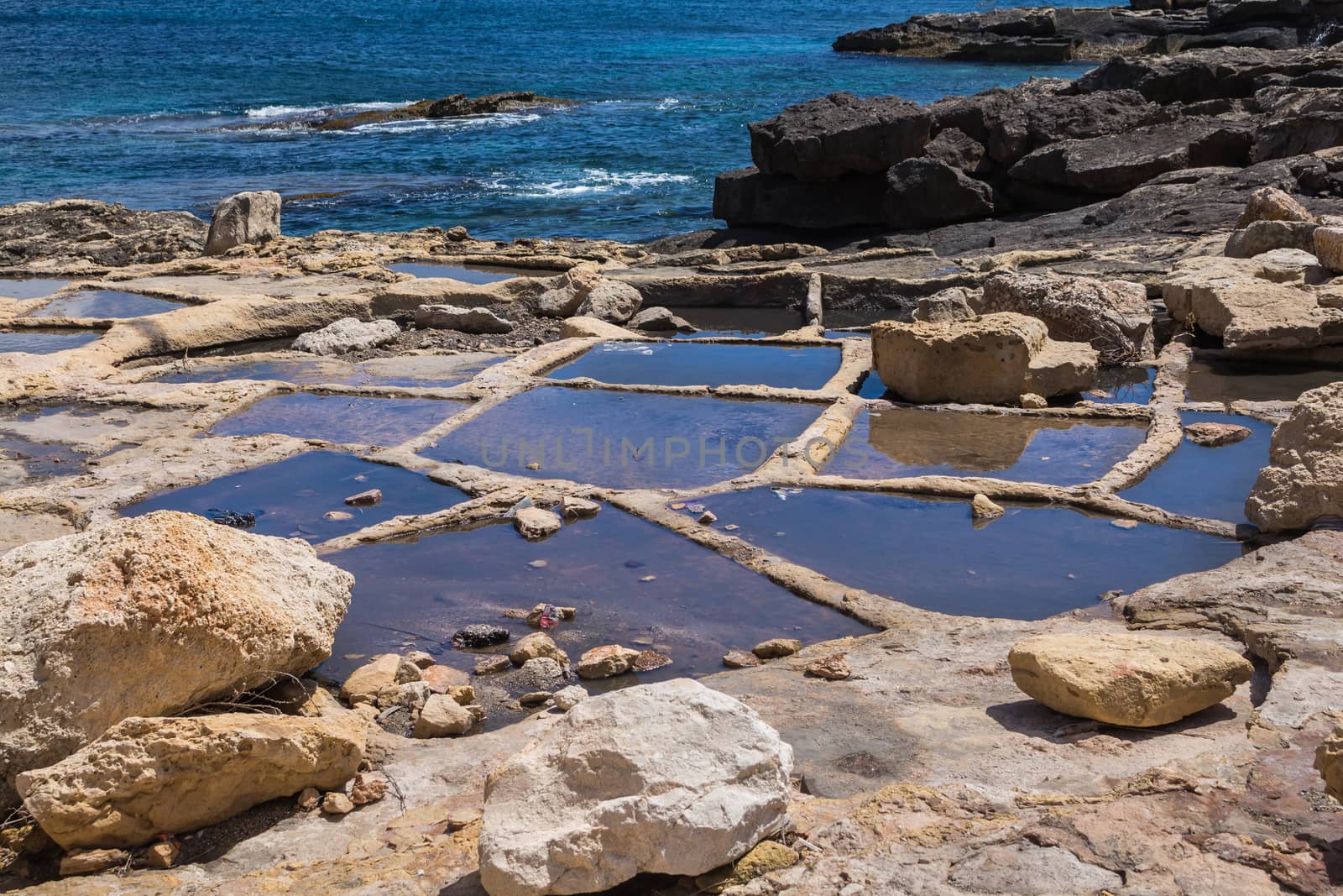 Holes in rocks at the seaside of the Mediterranean sea, for evaporation the water and getting sea salt. City Marsaskala, island Malta.