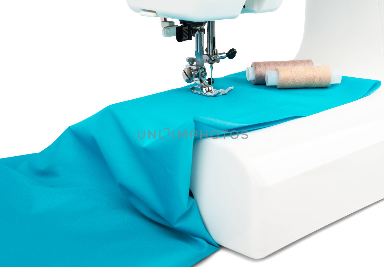 Electric sewing machine with blue cloth and spools of thread. Close-up