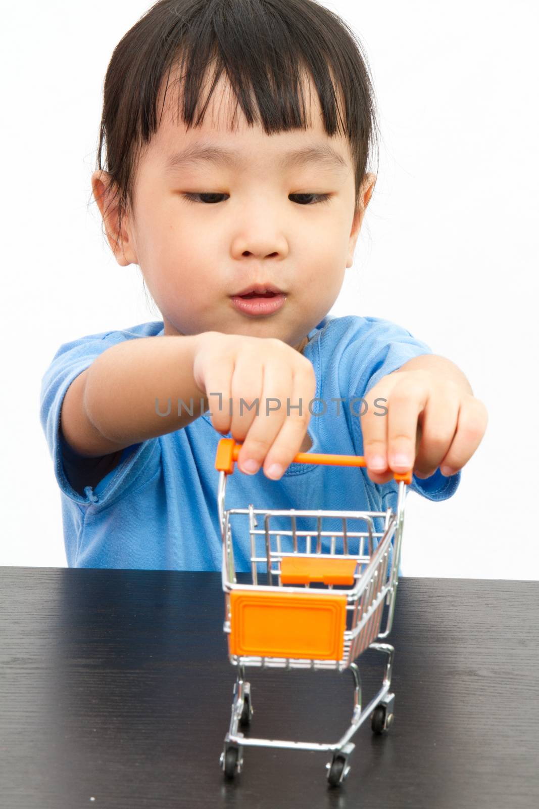 Chinese little girl pushing a toy shopping cart in plain white isolated background.