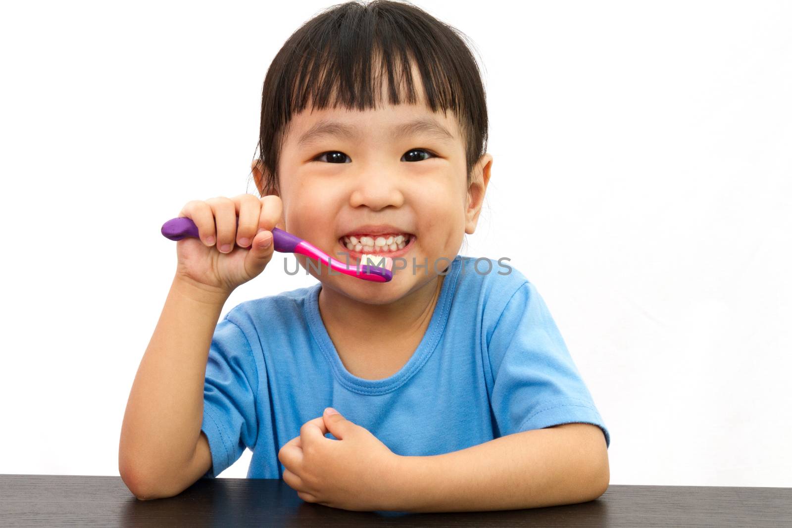 Chinese little girl brushing teeth in plain white isolated background.