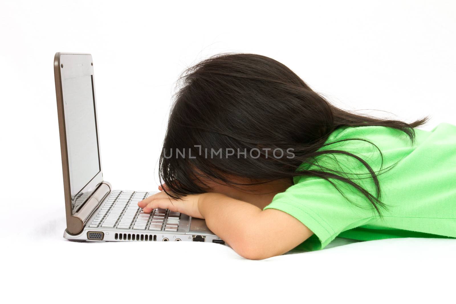 Chinese little girl sleep in front of a laptop in plain isolated white background.