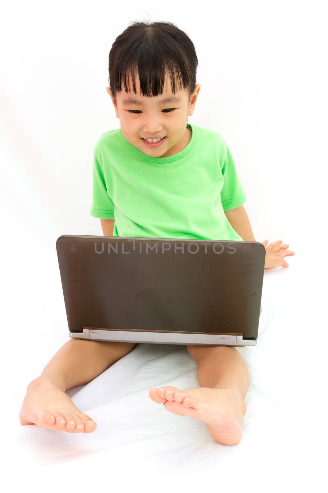 Chinese little girl sitting on floor with laptop by kiankhoon