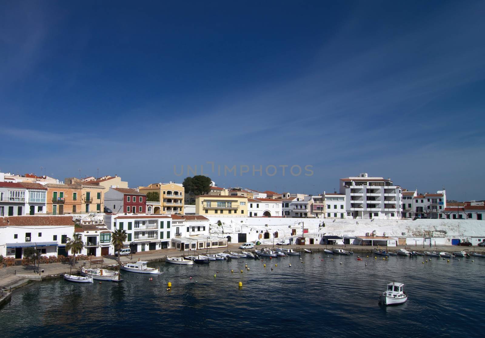 Es Castell Harbor and Small Boat in Lagoon on Blue Skies background, Menorca, Balearic Islands