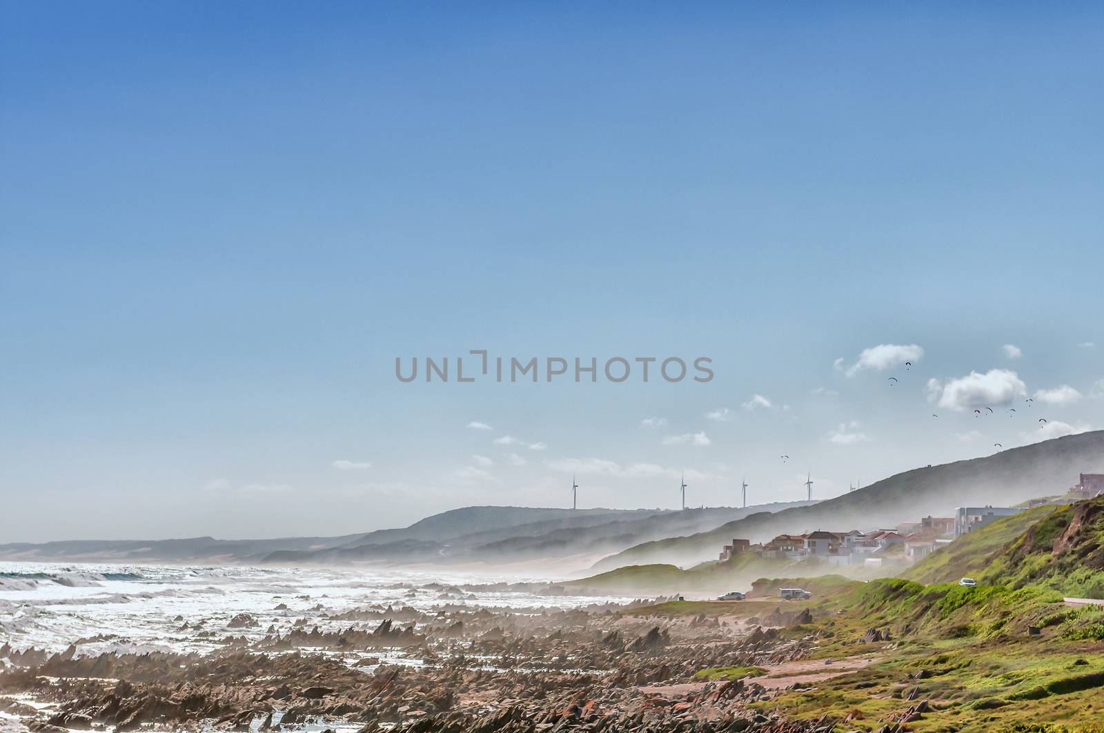 PORT ELIZABETH, SOUTH AFRICA - FEBRUARY 27, 2016:  Paragliders in the air at Beachview near Port Elizabeth with fog moving in. Wind turbines are visible