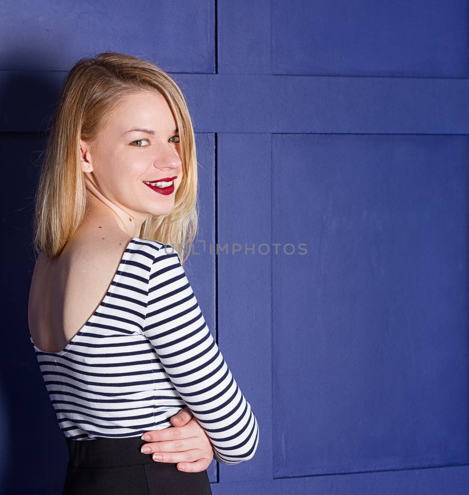 Beautiful blonde in a shirt-vest near a blue wall