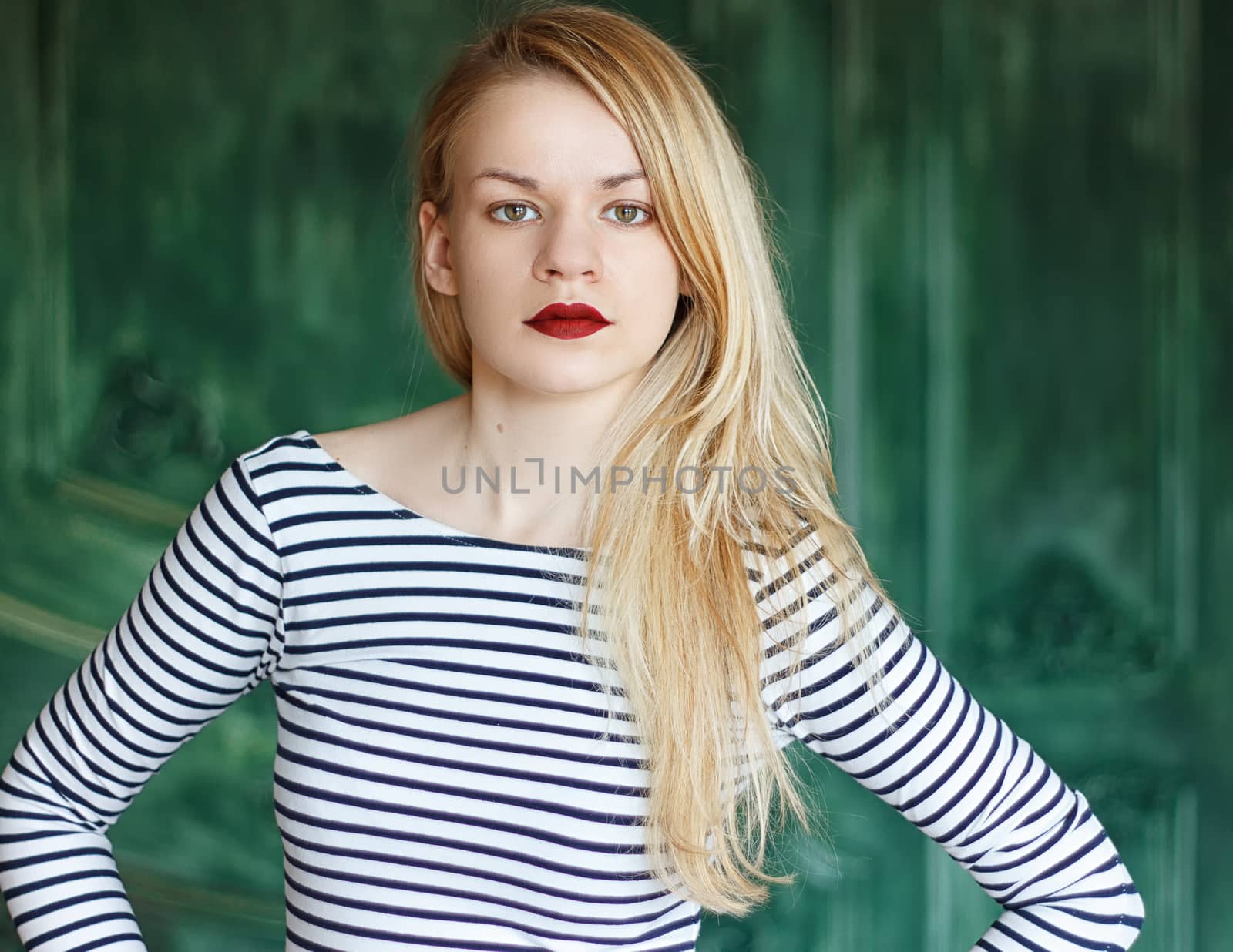 Blonde with red lips in a striped shirt on a green background a grunge wall