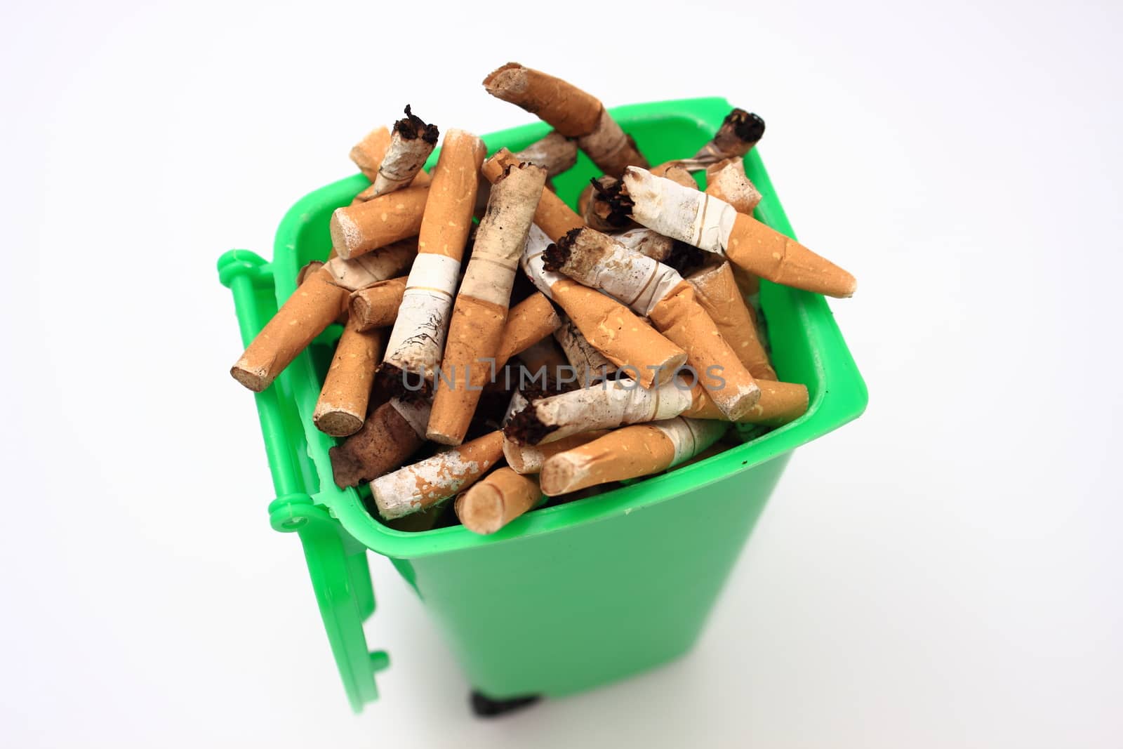 Used cigarette butts in green waste bin on white background