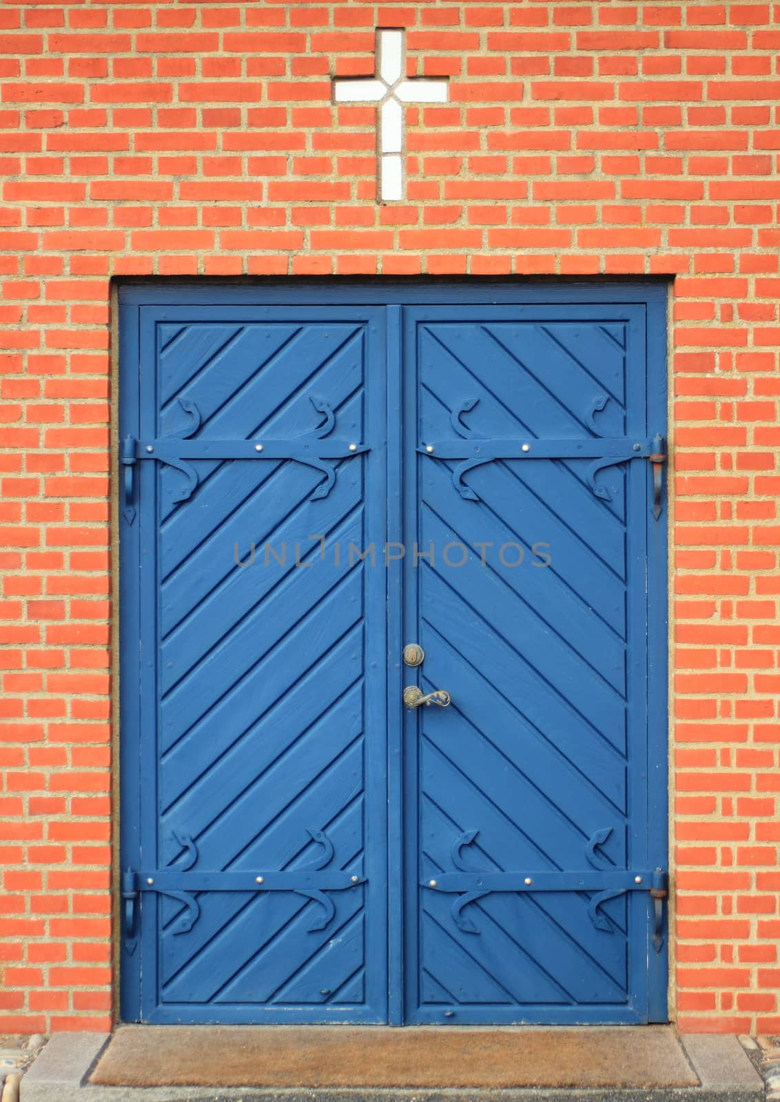 Isolated entrance to church with blue doors and white cross