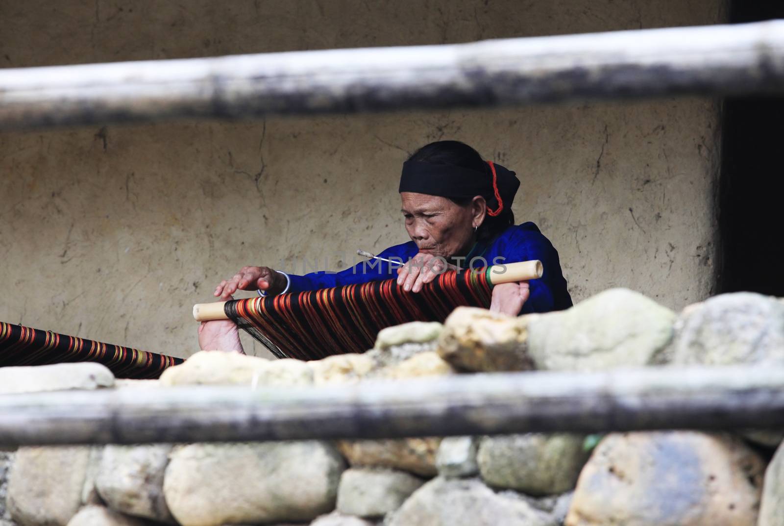 Hainan, China - April 7, 2012: Mature woman works on an ancient loom in Hainan. China