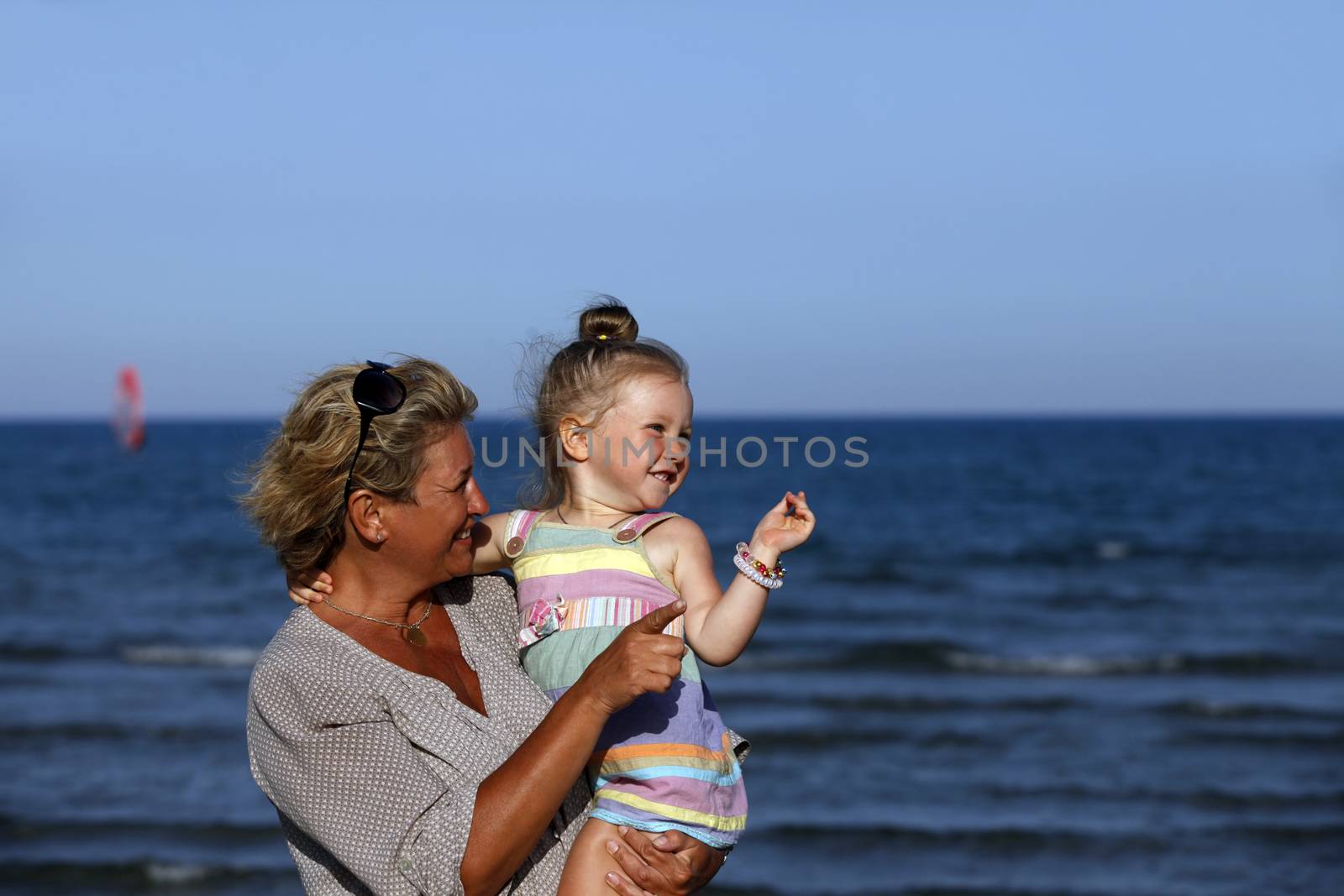 Grandmother with a little granddaughter on the beach