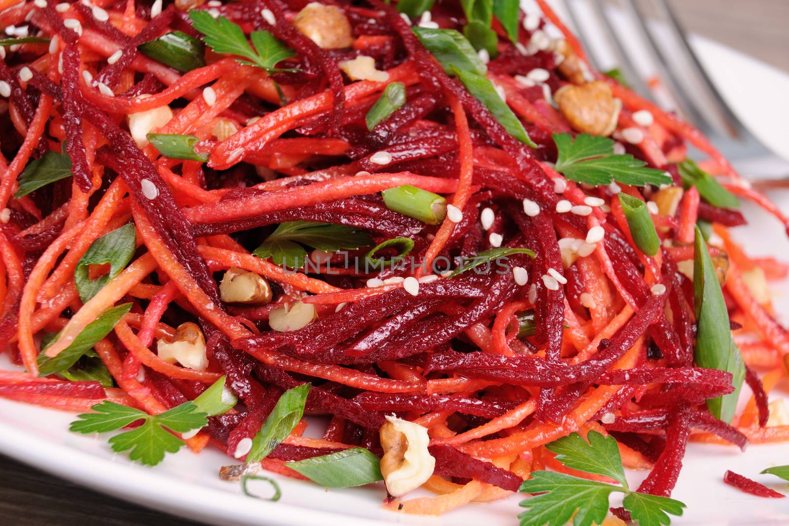 Salad of fresh grated carrots, beets, onions flavored with nuts and sesame seeds