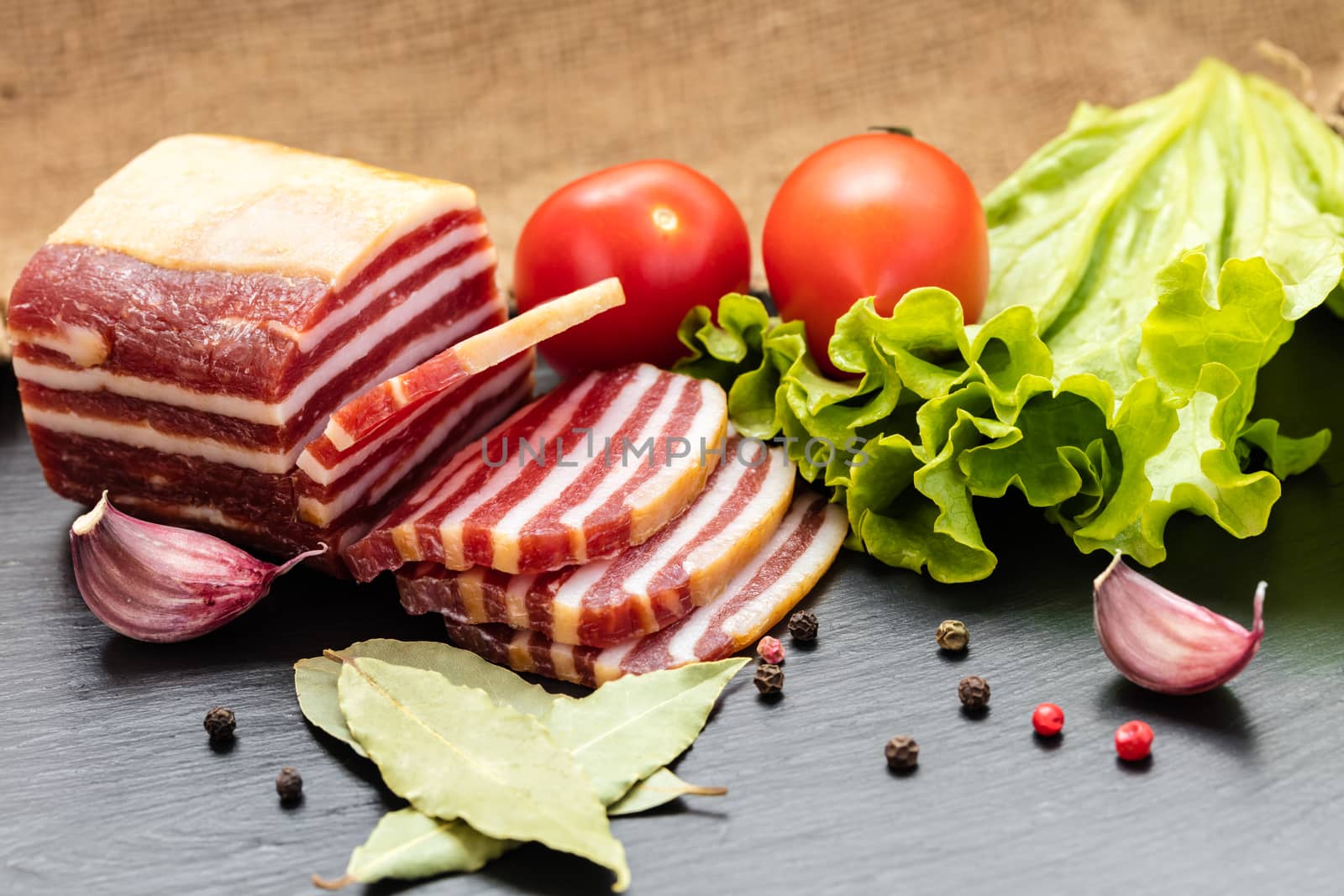 slices of sausage with bacon on a dark background